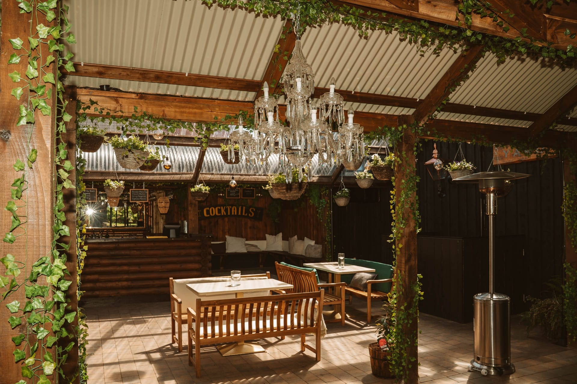 The cocktail bar pergola with crystal chandelier, ivy and hanging baskets